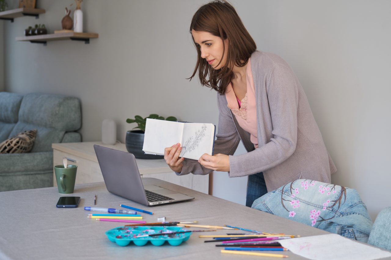 caucasian-influencer-woman-showing-her-sketchbook-to-her-community-in-a-stream--e1697192153498.jpg